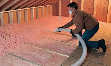 Man doing blown-in attic installation
